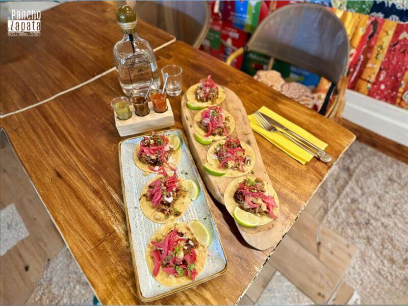tacos al pastor servidos junto a copa de tequila Patrón