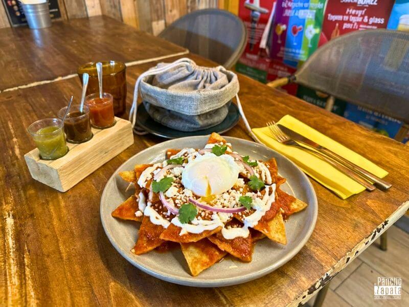 Plato de chilaquiles rojos mexicanos con crema y cebolla, ideal para la resaca
