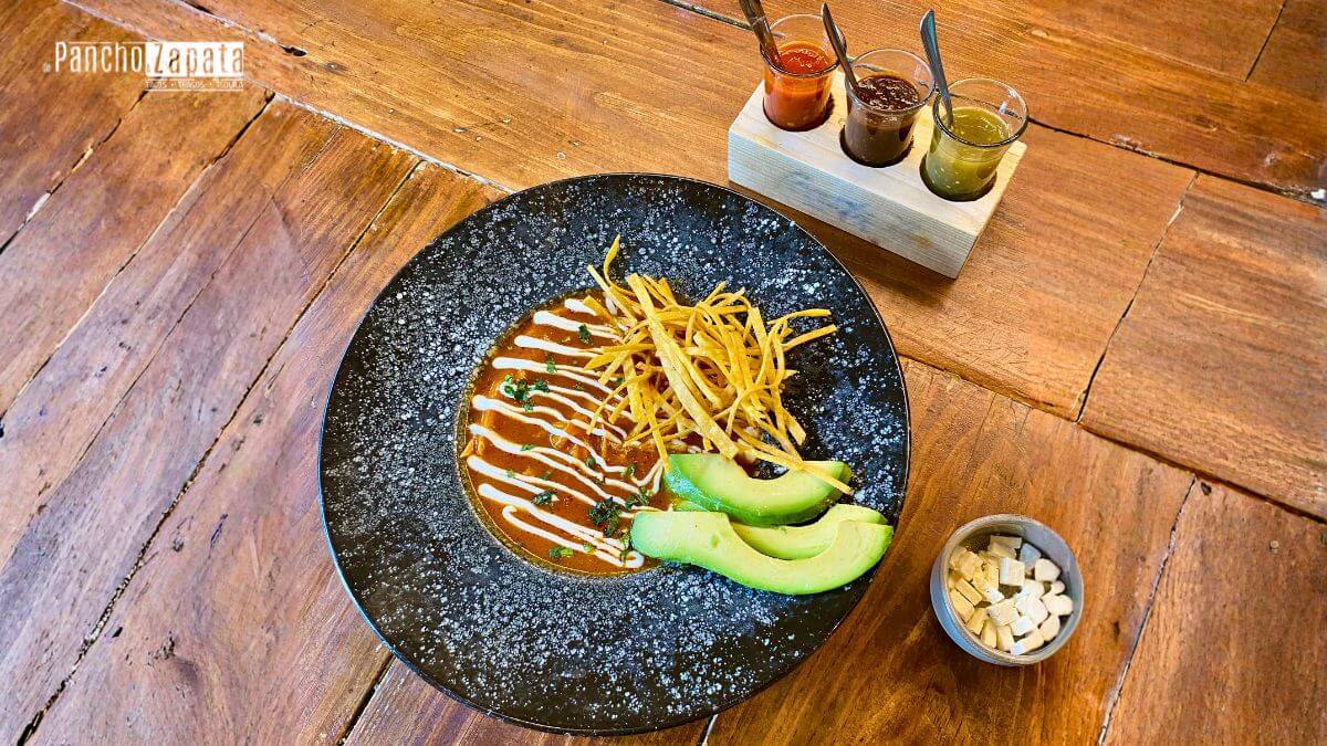 Primer plano de Sopa Azteca tradicional con tiras de tortilla, aguacate y chile pasilla, servida caliente en De Pancho a Zapata.