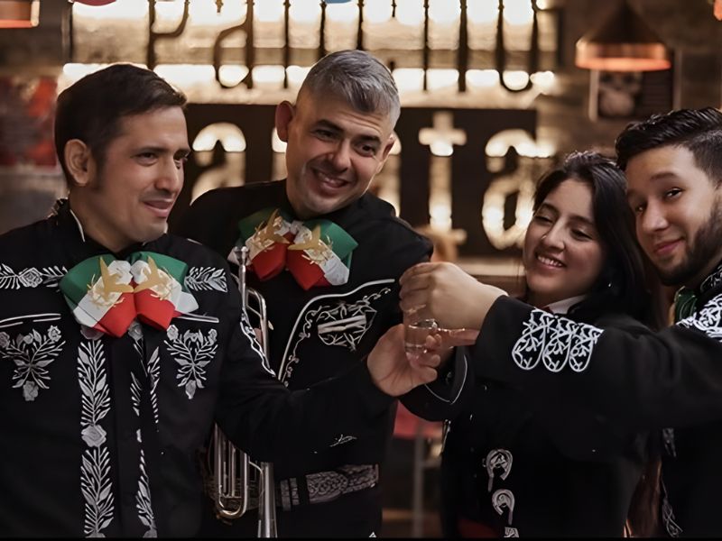 Clientes sonriendo, brindando con margaritas y disfrutando de la música de los mariachis en Torrelodones.