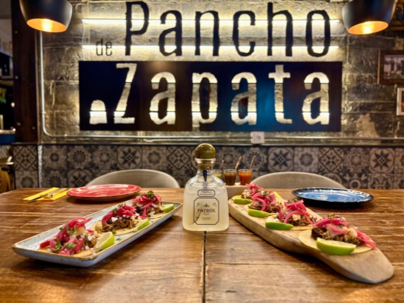 Tacos de barbacoa con cebolla morada encurtida y tequila Patrón sobre la mesa de De Pancho a Zapata