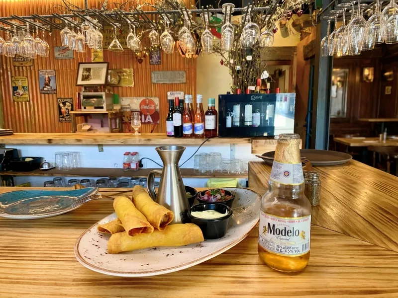 Flautas de pollo crujientes con pico de gallo, crema y cerveza Modelo en la barra